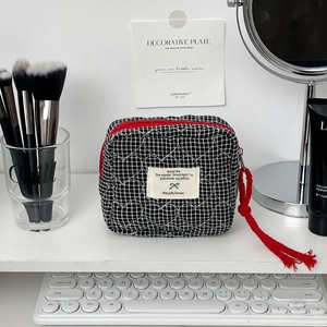 Détail de la trousse de toilette matelassée en cœurs à carreaux noir et blanc et zip rouge