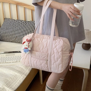 Sac de voyage matelassé cœur avec breloque Hello Kitty porté dans une chambre douce