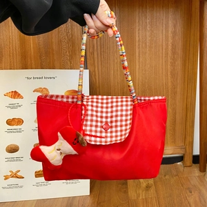 Detail view of red tote bag with colorful beaded handle and cute apple core plush charm