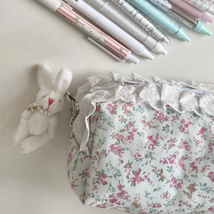 Gros plan sur une trousse à fleurs avec bordure en dentelle et porte-clé lapin peluche