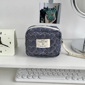 Détail de surpiqûre en cœur sur trousse de toilette à carreaux bleus avec anse