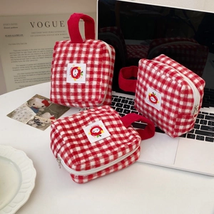 Close-up of red and white plaid toiletry bags with soft plush texture and side handles