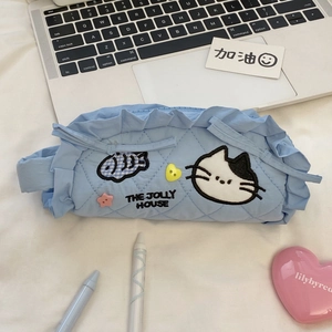 Dettaglio dell'astuccio trapuntato azzurro con ricamo di gatto e decoro bottoni a cuore