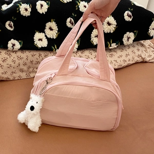 Pink quilted makeup bag with plush dog charm shown in a cozy domestic setting