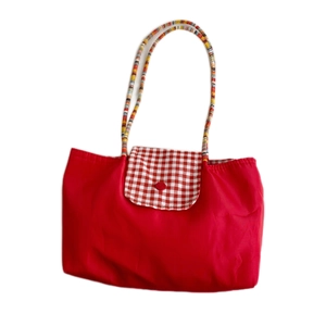 Minimalist red checkered tote bag with woven handles and button closure on white background