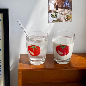 Close-up of minimalist tomato glass cups with straw on a wooden shelf in soft light