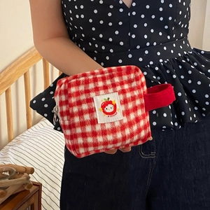 Close-up of red and white checkered plush makeup bag with a cute apple logo and red handle