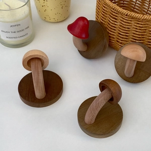 Detail of four mushroom-shaped wooden hooks in various colors for creative wall decor