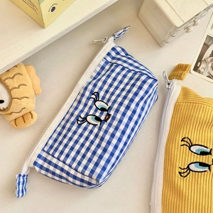 Detail of blue plaid and yellow corduroy stationery bags with cute eye embroidery