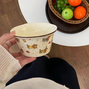 Close-up of cream ceramic bowl featuring cute cartoon puppy and cherry illustrations