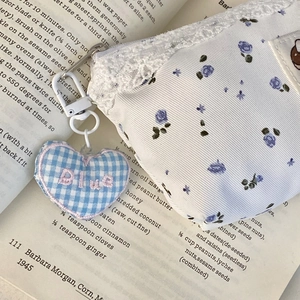 Floral cat pencil case with blue heart charm and lace detail on a vintage book background