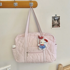 Détail du sac de voyage matelassé rose avec breloque peluche sur un cintre en bois