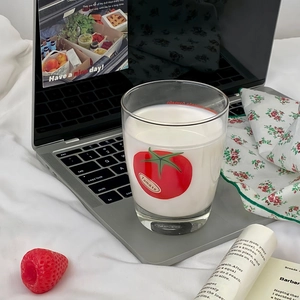 Close-up of minimalist tomato glass milk cup with red pattern on a laptop keyboard