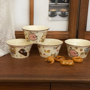 Close-up of four cream ceramic bowls with cute cartoon animal prints on wooden shelf