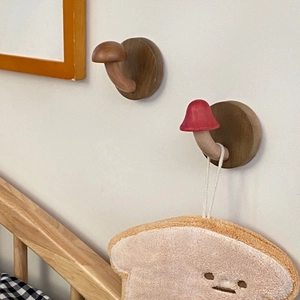 Detail of wooden mushroom wall hooks with natural wood grain and red cap design
