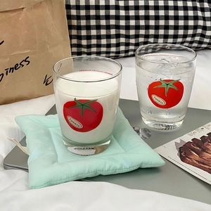 Detail shot of two cylindrical glass cups with red tomato prints in a cozy home setting