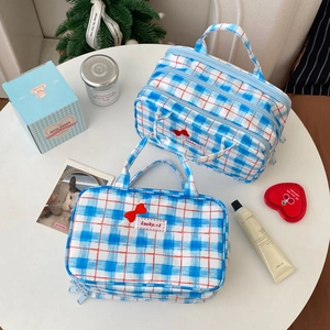 Close-up of blue gingham toiletry bag set with red bow embroidery and sturdy handle