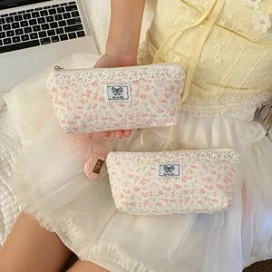 Close-up of floral canvas pencil case with lace trim and blue ribbon label detail