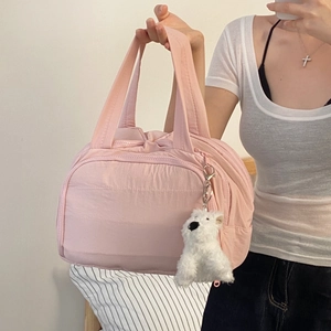 Detail of pink quilted nylon travel bag with zipper closure and cute plush dog charm