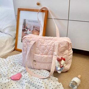 Détail du sac de voyage rose matelassé avec motifs de cœurs et poche zippée