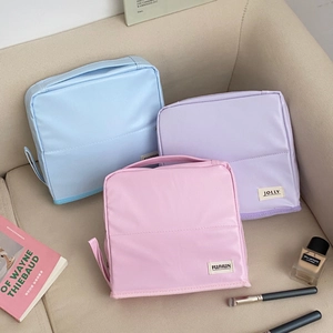 Stack of macaron-colored travel cosmetic bags in blue, purple, and pink waterproof fabric