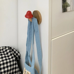 Macro detail of a red mushroom wooden wall hook with natural wood grain on a white wall