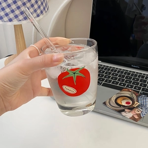 Detail of tomato pattern glass cup with straw, featuring ice and a minimalist design