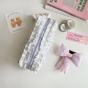Détail de la trousse à fleurs en dentelle avec bordure blanche et nœud rose soyeux
