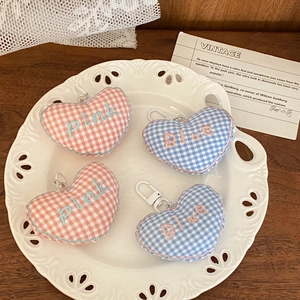 Close-up of heart-shaped plaid fabric keychains with embroidery in a decorative ceramic dish