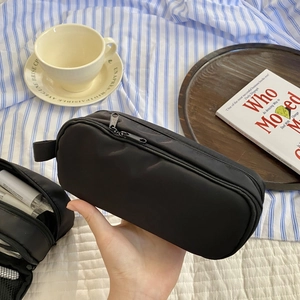 Handheld view of a black multi-layer large capacity pencil case with handy side strap