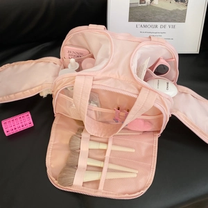 Detail of pink nylon travel makeup bag showing multi-compartment interior and brush slots