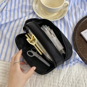 Close-up of a large black pencil case showing internal compartments with mesh pockets