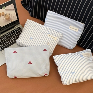 Detail of four assorted blue and white fabric makeup bags with bow embroidery and zippers