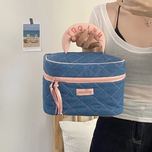 Detail of denim toiletry bag with pink quilted lattice and embroidered Melody handle