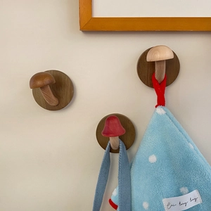 Detailed view of three mushroom-shaped wooden wall hooks holding a towel on a warm wall