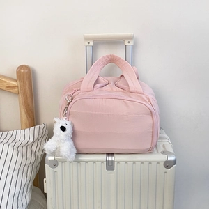 Pink travel organizer bag with double handles and cute teddy bear charm on suitcase