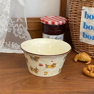 Detail of cream ceramic bowl featuring cute cartoon dogs and brown rim on wooden table