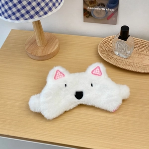 Close-up of cute white plush sleep mask with bear ears on a cozy wooden desk setup