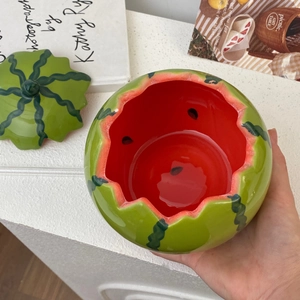 Detail of creative ceramic watermelon bowl with lid featuring realistic red glaze finish