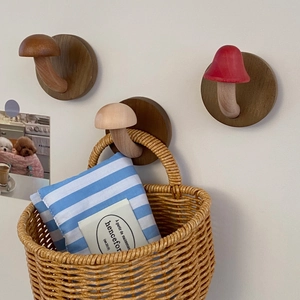 Three mushroom-shaped wooden wall hooks showing natural wood texture with hanging wicker basket