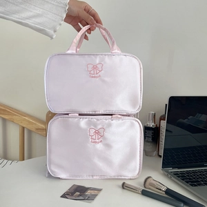 Close-up of pink satin makeup bags featuring embroidered bow design and silk handle