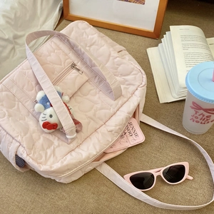 Sac de voyage rose matelassé avec motifs de cœurs, doubles poignées et bandoulière réglable