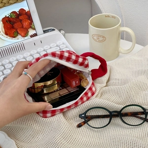 Detail view of red plaid plush makeup bag showing interior storage and silver zipper
