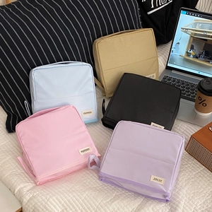 Detailed set of five macaron-colored travel toiletry bags in a cozy home setting