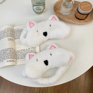 Detailed view of white plush Westie dog sleep mask with pink plaid ears on a white table