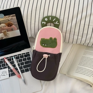 Close-up of pink and brown cartoon crocodile pencil case with green handle and JOLLY embroidery
