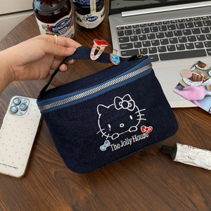 Denim Hello Kitty makeup bag with embroidery and top handle on a wooden desk