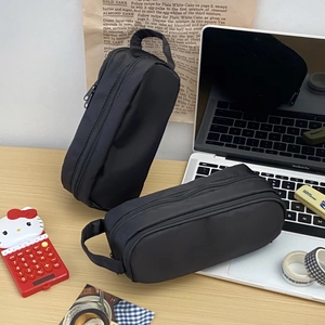 Detail shot of two large black canvas stationery bags with handles on a messy desk