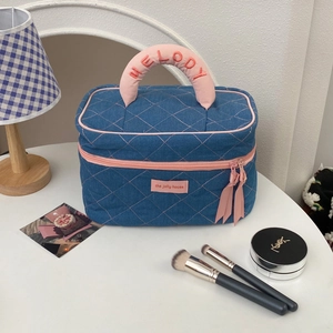 Detail of denim toiletry bag with pink quilted pattern and embroidered Melody handle