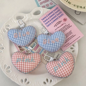 Detail of checkered heart keychains with blue and pink embroidery on white ceramic plate